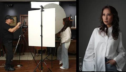 Professional portrait of a woman in white shirt against dark background, with behind-the-scenes studio setup visible on the left.