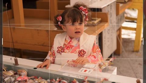 Young child with floral hair accessories gazing at jewelry display case.