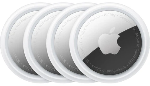 Four Apple AirTag tracking devices arranged in a row, showing white circular design with dark tracking element visible on rightmost unit.
