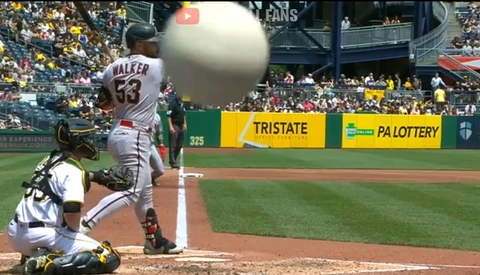 Baseball batter at plate during pitch, ball in motion, catcher and umpire visible behind.