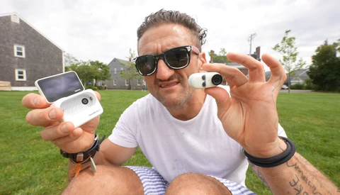 Man holding two compact cameras outdoors, displaying them toward the camera.