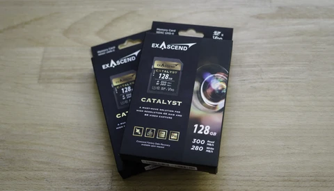 Three black boxes of Exascend Catalyst CompactFlash memory cards with 128GB capacity displayed on a wooden surface.