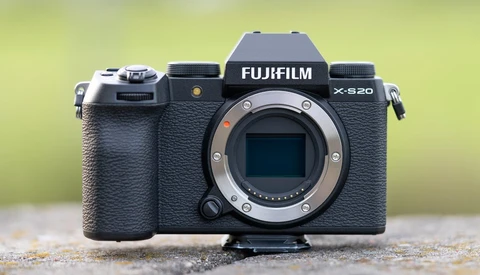 Fujifilm X-S20 mirrorless camera body with lens mount exposed against blurred yellow-green background.
