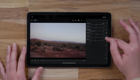 Tablet displaying desert landscape photo in editing software with adjustment panels visible on right side.