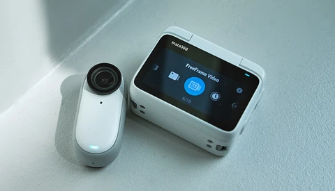 White action camera and portable gimbal stabilizer displayed on a light gray surface.