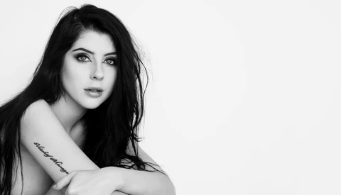 Black and white portrait of a woman with long dark hair, looking over her shoulder with a subtle expression.