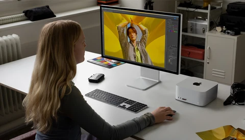 Designer working on portrait photo editing in Adobe Lightroom with vibrant yellow background on monitor.