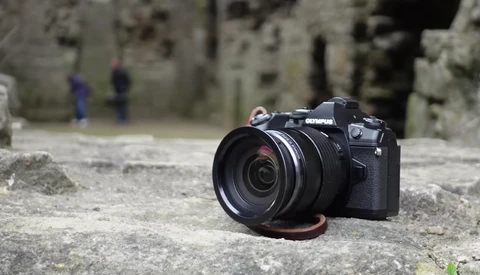 Olympus camera with attached lens resting on weathered concrete surface.