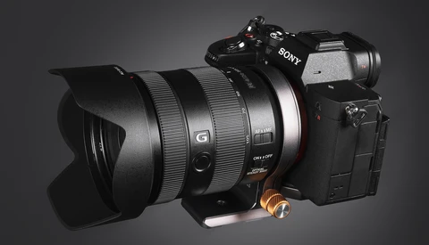 Sony mirrorless camera with wide-angle lens and lens hood mounted on gray background.