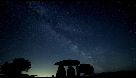 Silhouetted ancient stone structure against night sky filled with Milky Way stars.