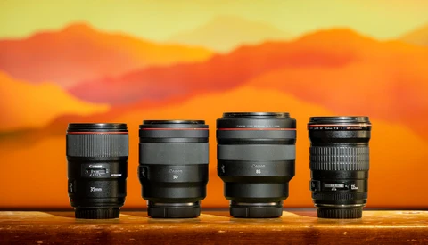 Four camera lenses arranged in a row against a warm sunset sky backdrop.