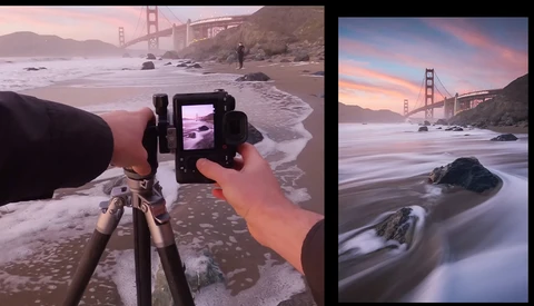 Photographer composing long exposure beach shot with tripod-mounted camera while viewing Golden Gate Bridge at sunset.