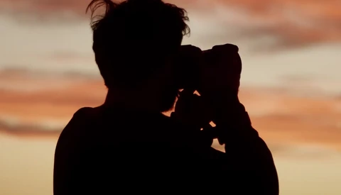 Silhouetted figure holding a child against a golden sunset sky.