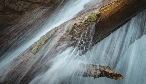 Flowing water cascades over layered rock formations with silky motion blur effect.