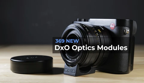 DxO camera with interchangeable lens module and lens cap on wooden surface.