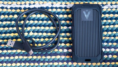 External SSD with USB cable on a patterned textile background.