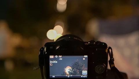Camera LCD screen displaying a nighttime scene with bokeh lights in the background.