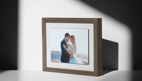 Framed photograph of a couple embracing outdoors displayed in a rustic wood frame with white mat.