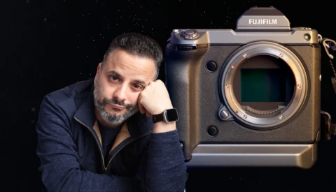 Photographer posing next to a Fujifilm medium format camera body against a dark starry background.