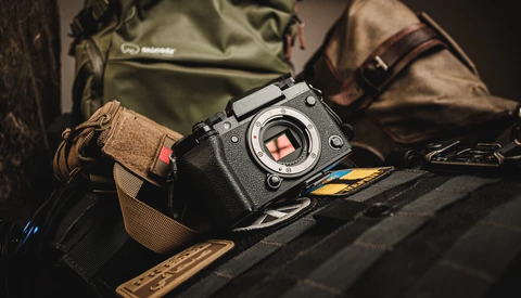 Black mirrorless camera with visible sensor positioned on photography gear and canvas bags.