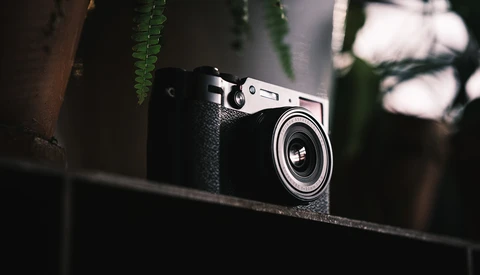 Vintage rangefinder camera with black leather body and chrome top plate resting on a dark surface.