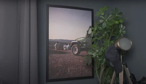 Framed photograph of a vintage truck and figure in an arid landscape displayed on a gallery wall.