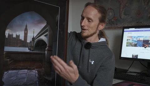 Photographer reviewing a large-format print of Big Ben and Westminster Bridge displayed on a monitor in a studio workspace.