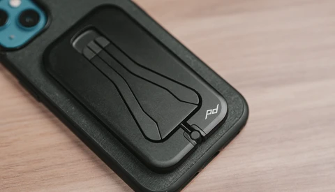 Black smartphone case with integrated magnetic stand mounted on a blue-trimmed phone.