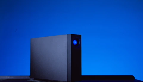Black desktop computer tower with illuminated blue power button against deep blue gradient background.
