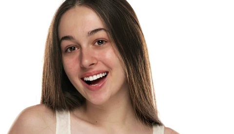 Woman with long dark hair smiling brightly against a white background.