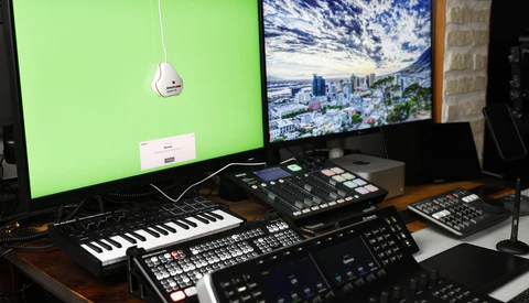 Music production studio setup with dual monitors, keyboard controllers, and audio equipment on wooden desk.
