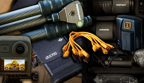 Professional photography gear laid out including light stands, flash units, cables, and a compact camera.