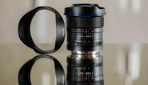 Two vintage manual focus lenses with lens hoods displayed against a neutral background with reflections.