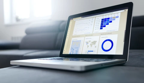 Laptop displaying a dashboard with data visualizations including charts, graphs, and a blue pie chart.