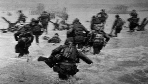Soldiers wading through ocean water during an amphibious landing operation.
