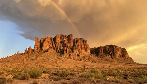 Desert butte with jagged rock formations under golden hour light and dramatic storm clouds.