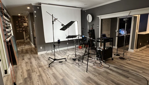 Professional photography studio setup with softbox lighting, backdrop stand, and equipment on wooden flooring.