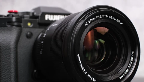 Fujifilm mirrorless camera with a 57mm f/1.2 STM ASPH lens mounted, shot against a snowy background.