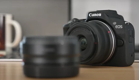 Canon EOS mirrorless camera with interchangeable lens on wooden surface.