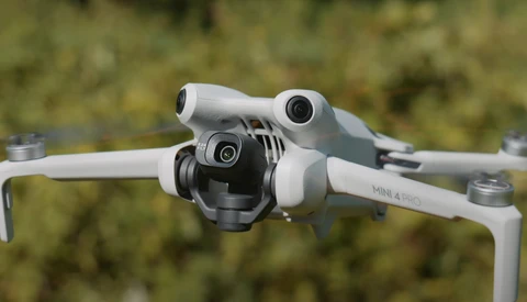 DJI Mini 4 Pro drone photographed from above against a blurred green foliage background.