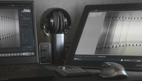 Professional audio editing workstation with dual monitors, headphones, and mixing equipment.