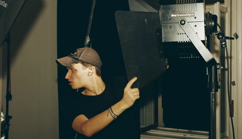 Photographer adjusting a professional LED light panel mounted on a stand in a studio setting.