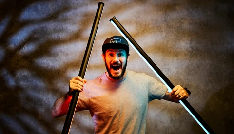 Enthusiastic man holding two poles with dramatic studio lighting and textured background.