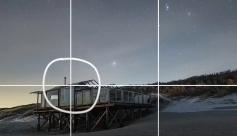 Beach structure with grid overlay and circular framing guide positioned over wooden platform building.