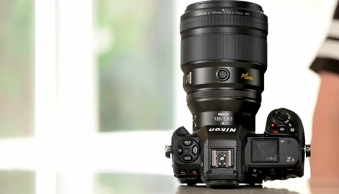 Nikon Z mirrorless camera with attached telephoto lens mounted on white surface.