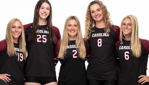 Five volleyball players in black uniforms with Carolina branding posed together for a team portrait.