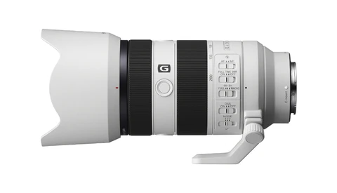 Side view of a mirrorless telephoto lens with white barrel, black focus ring, and control buttons.