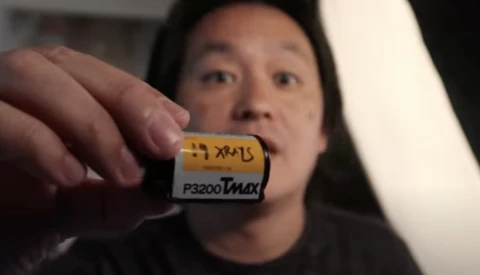 Person holding a vintage film cartridge labeled P3200 Tmax against blurred background.