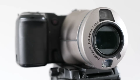 Silver camcorder with black handle shown alongside blurred dark compact camera against white background.