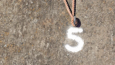 White number 5 painted on weathered concrete surface with rope and pulley attached above.